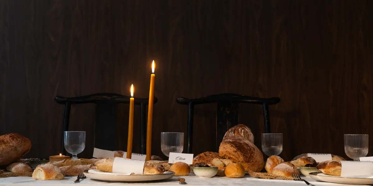 Editorial dining table styled with artisan bread, tall candles, ceramic plates and glassware for a creative brand experience.